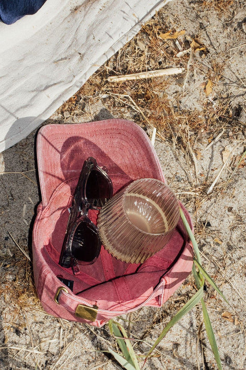A Djuce Studio Unbreakable Wine Glass lying in a cap on the beach