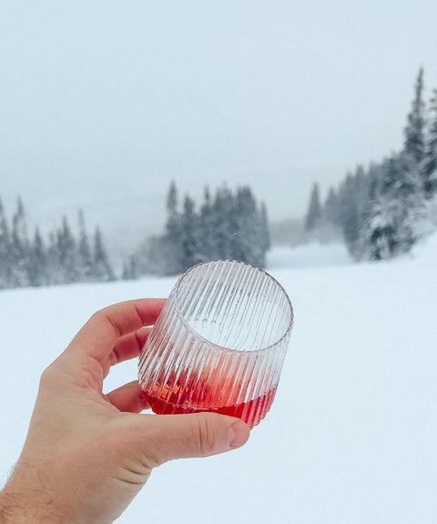 Hand holding the Djuce Studio Unbreakable Wine Glass in a ski slope